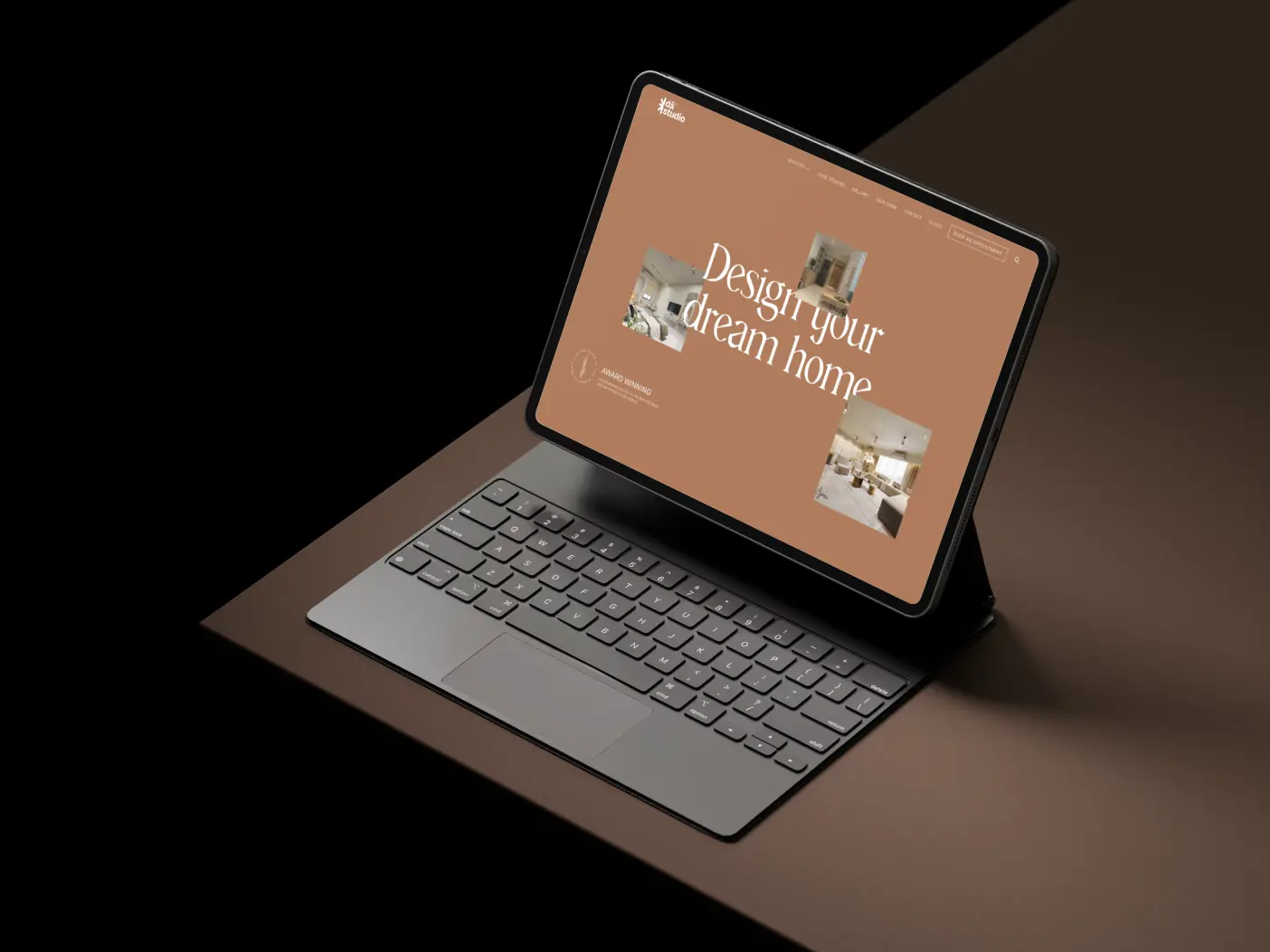 Tablet with a keyboard case mockup displaying the DA Studio website homepage, featuring the 'Design your dream home' headline and project images on a brown background.