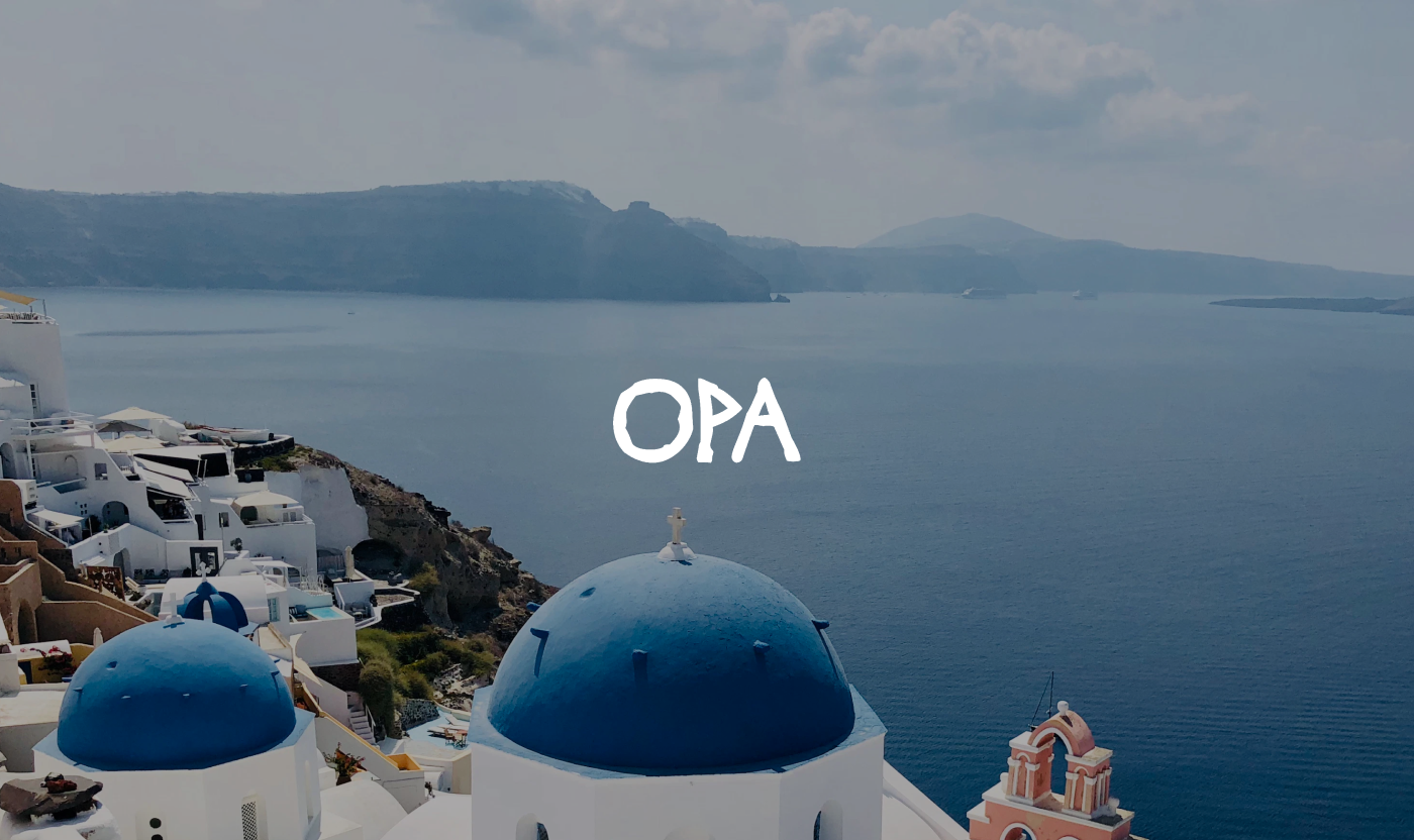 White OPA brand logo overlaid on a scenic view of Santorini's blue-domed white buildings overlooking the sea.