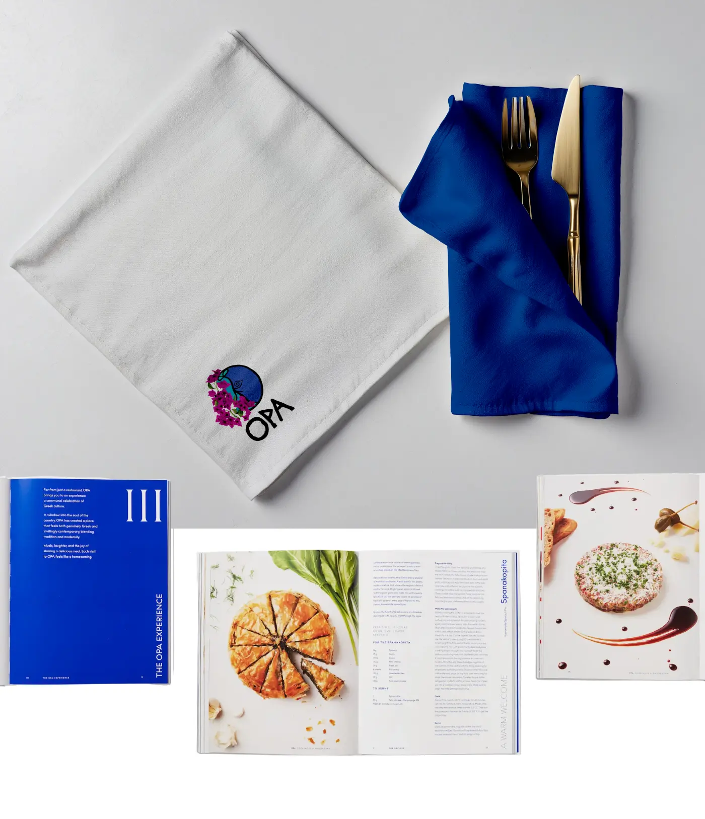 Branded restaurant napkin and golden cutlery set next to open pages of an OPA recipe book.