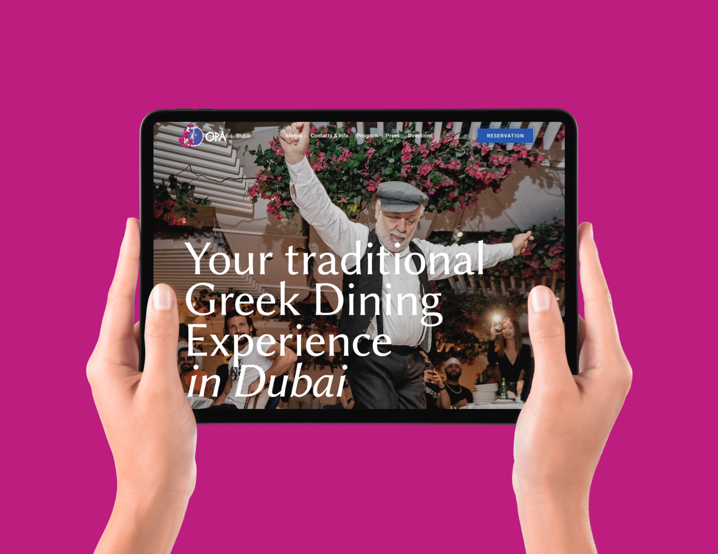 Hands holding a tablet displaying the OPA Dubai reservation webpage with a dancing Greek performer.