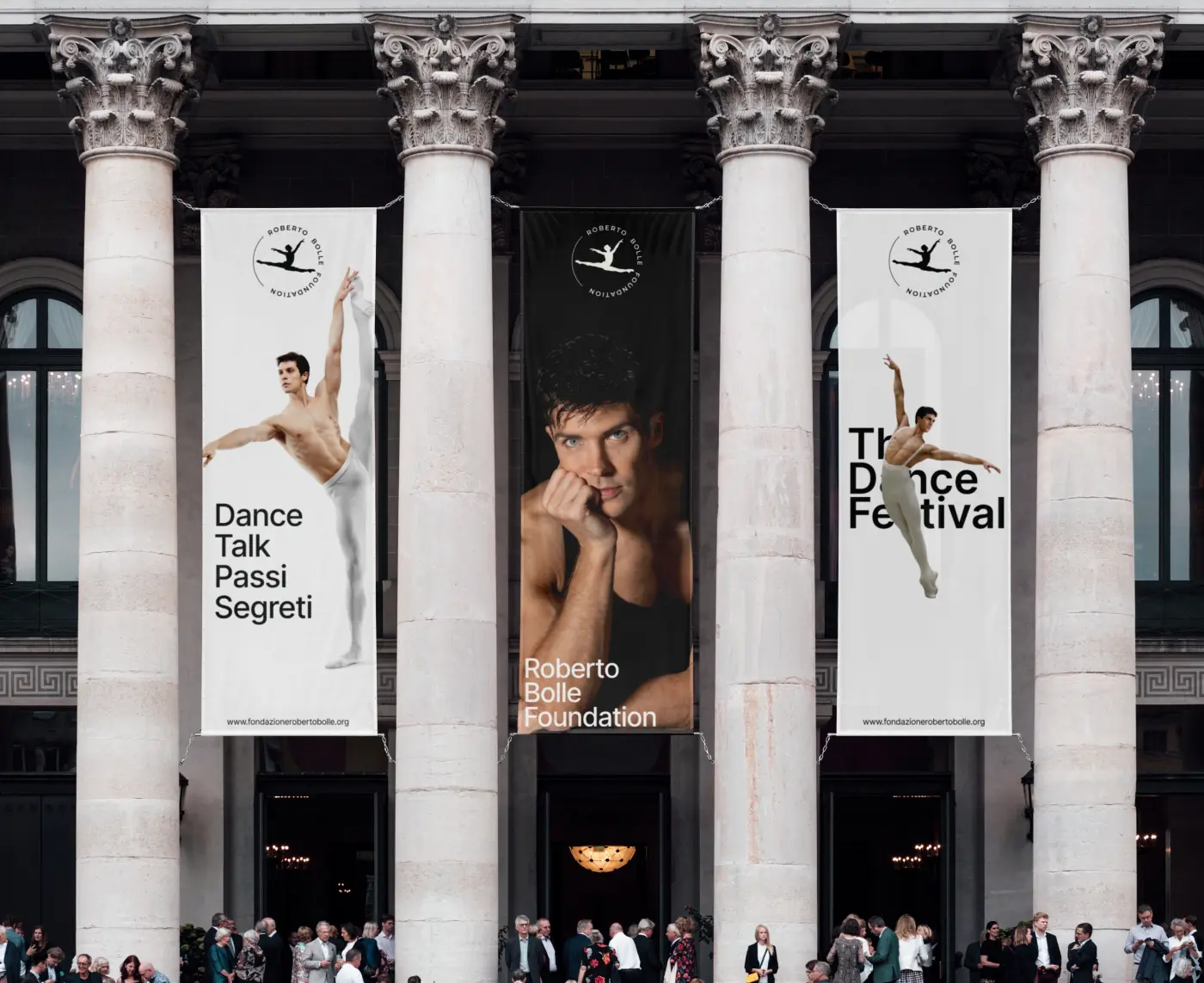 Three large vertical promotional banners hanging between classical building columns above a crowd of people.
