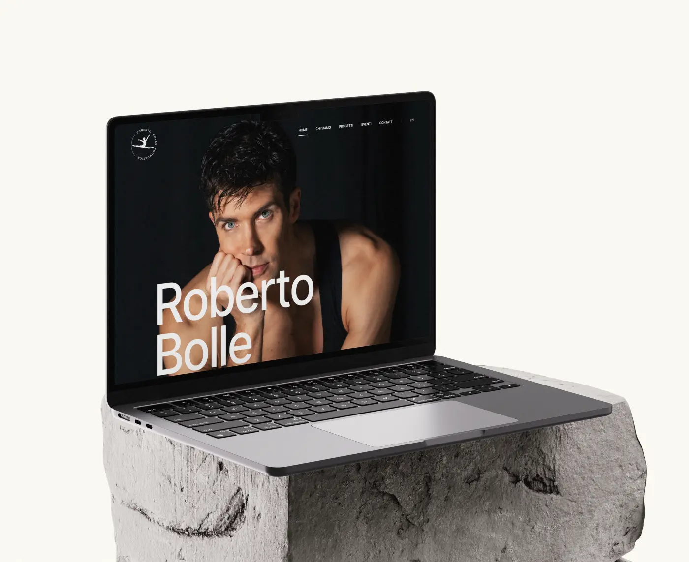 A laptop mockup sitting on a gray rock pedestal, displaying the Roberto Bolle Foundation website homepage.